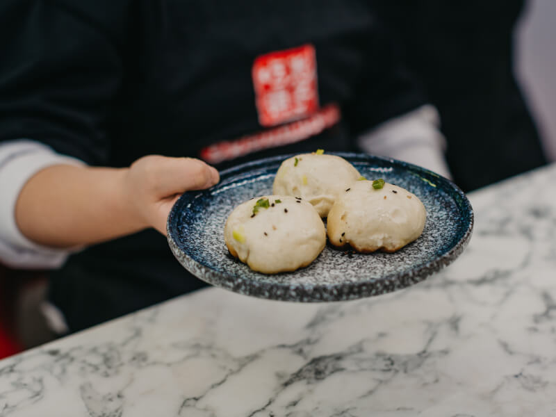 A person holding a plate of dumplings. 